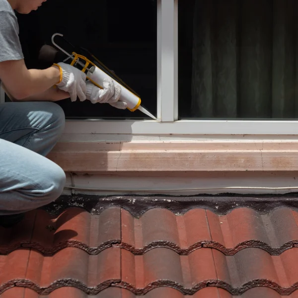 Un homme utilise un pistolet à clous pour réparer une fenêtre, illustrant un travail de rénovation efficace.