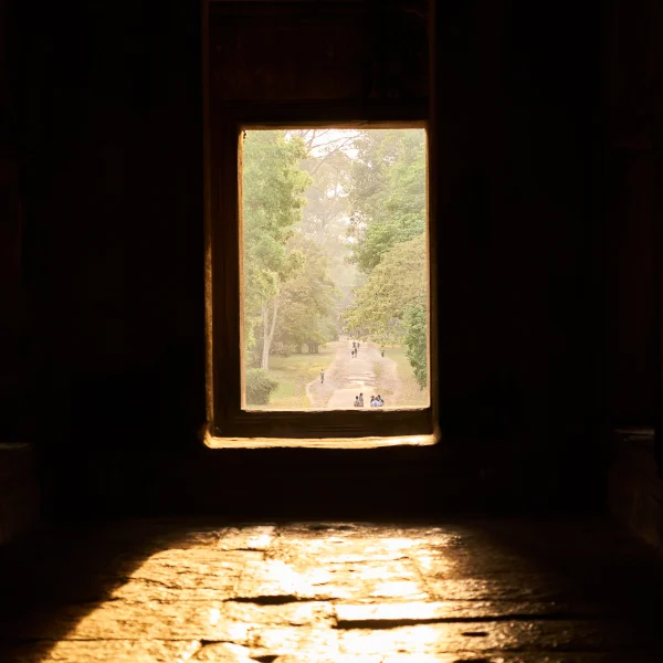 Une fenêtre ancienne avec la lumière du soleil qui filtre à travers, située dans un bâtiment historique.